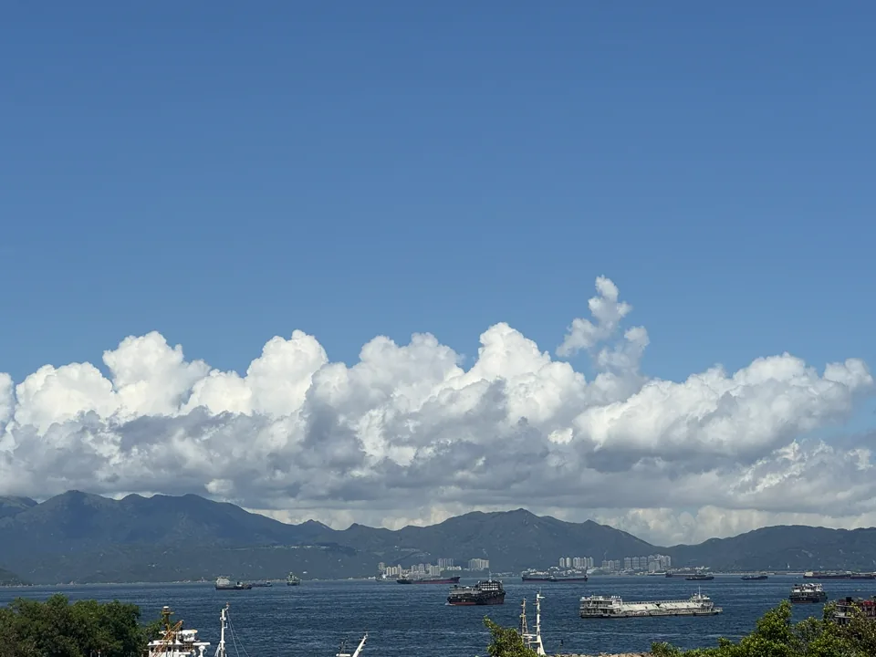 大团白云覆盖山脉与繁忙海面