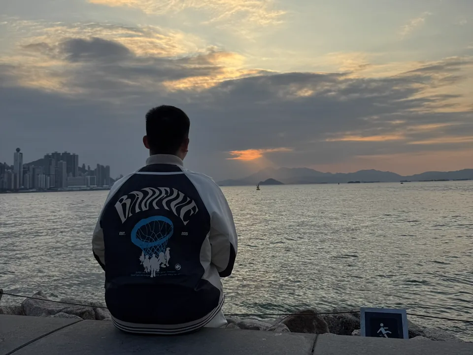 一人坐在海边望向落日与远山