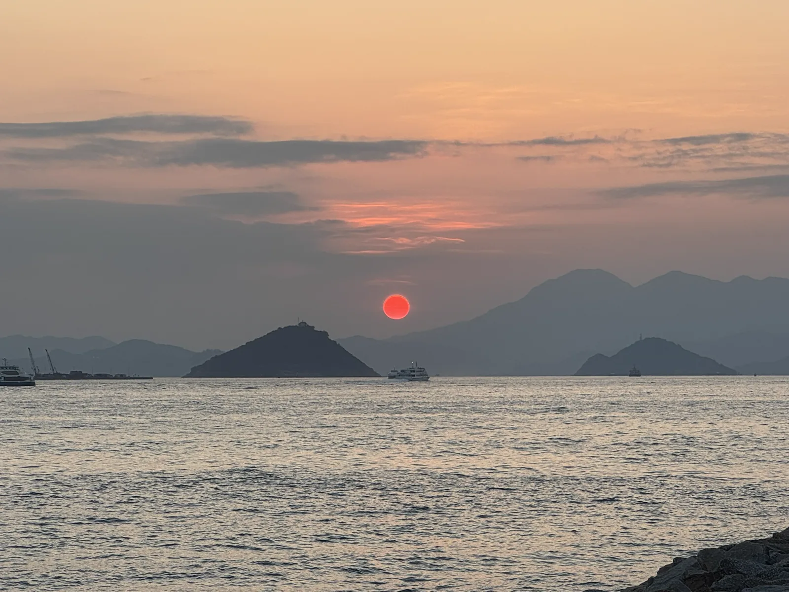 红日落在海面与群山之间